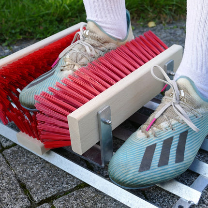 Fußball-Schuhe werden auf einem Schuhabtreter mit Bürsten gereinigt. 